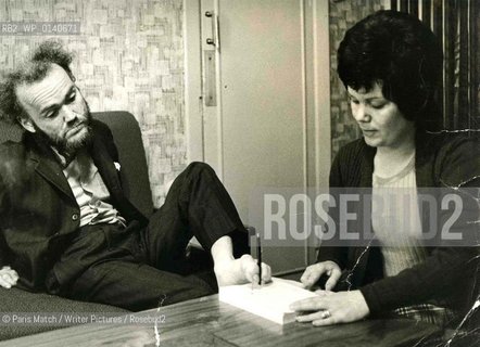 Christy Brown disabled Irish writer. Posing for a photographer from Paris Match in 1971.His wife Ann holds a copy of the bestselling  Down all the days  so that Christy can sign it...Copyright©Paris Match/Writer Pictures/Rosebud2