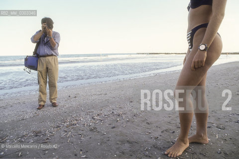 Venice Lido, Venice Film Festival, about 1990. A photographer shooting a starlet on the beach / Lido di Venezia, Mostra del Cinema di Venezia, 1990 circa. Un fotografo ritrae una starlette sulla spiaggia - ©Marcello Mencarini/Rosebud2