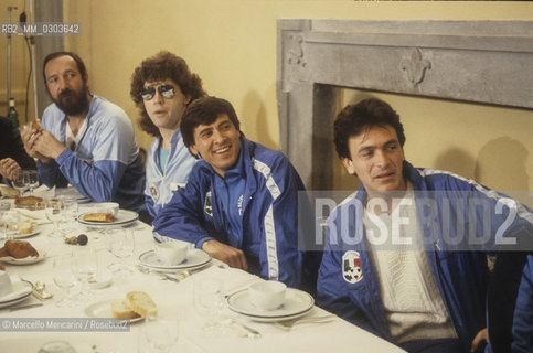 Italian National Singers Football Team, 1987. Italian pop singers Andrea Mingardi, Lanfranco Carnacina, Gianni Morandi and Riccardo Fogli eat with the team / Nazionale italiana cantanti 1987. I cantanti Andrea Mingardi, Lanfranco Carnacina, Gianni Morandi e Riccardo Fogli mentre mangiano con la squadra - ©Marcello Mencarini/Rosebud2