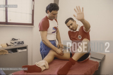 Italian National Singers Football Team, 1987. Masseur Nicola Mancuso massages singer Eros Ramazzotti in the locker room / Il massaggiatore Nicola Mancuso con il cantante Eros Ramazzotti in spogliatoio - ©Marcello Mencarini/Rosebud2