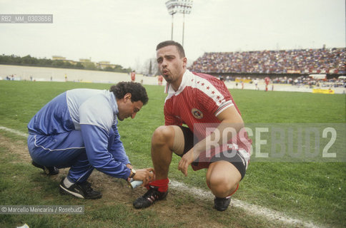 Italian National Singers Football Team, 1987. Masseur Nicola Mancuso massages singer Eros Ramazzotti on the game field / Il massaggiatore Nicola Mancuso con il cantante Eros Ramazzotti in campo - ©Marcello Mencarini/Rosebud2