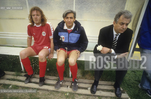 Italian National Singers Football Team, 1987. Singer Umberto Tozzi, lyricist Alfredo Rapetti (also known as Cheope) and coach Gino Pivatelli / Nazionale italiana cantanti, 1987. Il cantante Umberto Tozzi, il paroliere Alfredo Rapetti (nome darte Cheope) e lallenatore Gino Pivatelli in panchina - ©Marcello Mencarini/Rosebud2