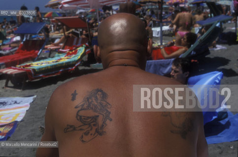 Ostia Lido, 1999. Tattooed man. Ostia is a beach town near Rome. In the summer time many people from Rome go there to the sea, particularly young suburban people said in slang coatti / Lido di Ostia, 1999. Uomo tatuato. Ostia è la spiaggia dei romani. Destate è frequentata in particolare dai giovani che abitano le borgate della periferia, i cosiddetti coatti- ©Marcello Mencarini/Rosebud2