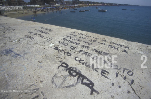 Ostia Lido, 1999. Lyrics of a song by rapper Er Piotta written on the parapet of a wharf.  Ostia is a beach town near Rome. In the summer time many people from Rome go there to the sea, particularly young suburban people said in slang coatti: Er Piotta is their favorite singer, now / Lido di Ostia, 1999. Versi di una canzone del rapper Er Piotta scritti sul pontile. Ostia è la spiaggia dei romani. Destate è frequentata in particolare dai giovani che abitano le borgate della periferia, i cosiddetti coatti: Er Piotta attualmente è il loro cantante di riferimento - ©Marcello Mencarini/Rosebud2