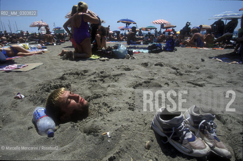 Beach bathers in Ostia Lido, 1999. Ostia is a beach town near Rome. In the summer time many people from Rome go there to the sea, particularly young suburban people said in slang coatti / Bagnanti sul Lido di Ostia, 1999. Ostia è la spiaggia dei romani. Destate è frequentata in particolare dai giovani che abitano le borgate della periferia, i cosiddetti coatti- ©Marcello Mencarini/Rosebud2