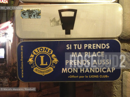 France, Provence, November 2012. Notice under a road signal indicating parking for disabled persons (if you take my place even take my handicap) / Francia, Provenza, Novembre 2012. Cartello sotto un segnale stradale che indica un parcheggio per automobilisti con handicap (se prendi il mio posto prendi anche il mio handicap) - ©Marcello Mencarini/Rosebud2