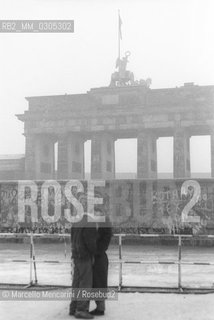 West Berlin, 1989. Couple kissing in front of the Brandeburg Gate / Berlino Ovest, 1989. Coppia che si bacia davanti alla Portra di Brandeburgo - ©Marcello Mencarini/Rosebud2