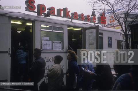 Berlin, 1989. Citizens of the East Germany in the queue at the counter of a West Berlin bank to collect a bonus of 100 marks, gift of the West Germany / Berlino, 1989. Cittadini della Germania Est in coda allo sportello di una banca di Berlino Ovest per riscuotere un bonus di 100 marchi, regalo della Germania Ovest - ©Marcello Mencarini/Rosebud2