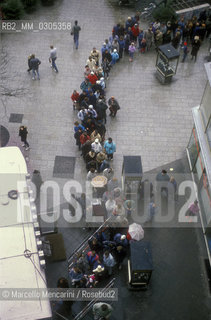 East Berlin, 1989. Citizens of the East Germany in the queue at the mobile counter of a West Berlin bank to collect a bonus of 100 marks, gift of the West Germany after the opening of the border between East Germany and West Germany / Berlino Est, 1989. Cittadini della Germania Est in coda allo sportello mobile di una banca di Berlino Ovest per riscuotere un bonus di 100 marchi, regalo della Germania Ovest dopo lapertura delle frontiere tra Germania Est e Germania Ovest - ©Marcello Mencarini/Rosebud2