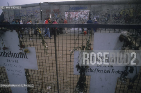 West Berlin, November 1989. The Berlin Wall after the opening of the border between East Germany and West Germany. In the foreground, some cross shape plates in memory of persons died attempting to cross the wall during the Cold War / Berlino Ovest, novembre 1989. Il Muro di Berlino dopo la dichiarazione dellapertura delle frontiere tra Germania Est e Germania Ovest. In primo piano, alcune targhe a forma di croce in memoria delle persone che cercarono di oltrepassare il muro durante la guerra fredda - ©Marcello Mencarini/Rosebud2