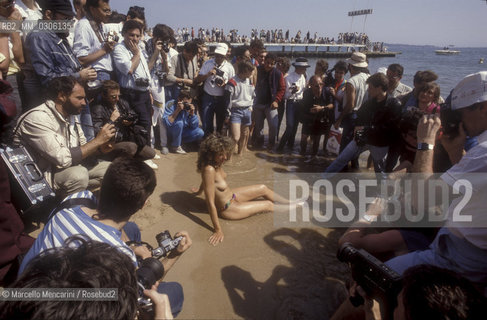 37th Cannes Film Festival, 1984. Photographers shooting a topless starlet on the beach / 37° Festival di Cannes, 1984. Fotografi intorno a una starlette in topless sulla spiaggia - ©Marcello Mencarini/Rosebud2