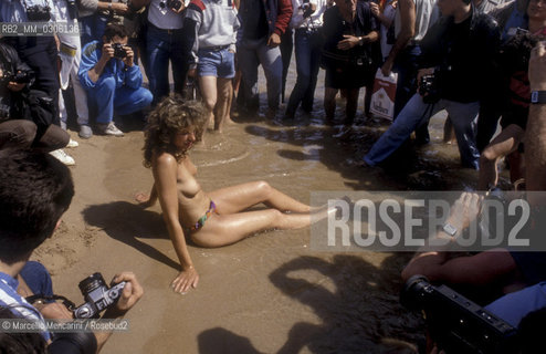 37th Cannes Film Festival, 1984. Photographers shooting a topless starlet on the beach / 37° Festival di Cannes, 1984. Fotografi intorno a una starlette in topless sulla spiaggia - ©Marcello Mencarini/Rosebud2