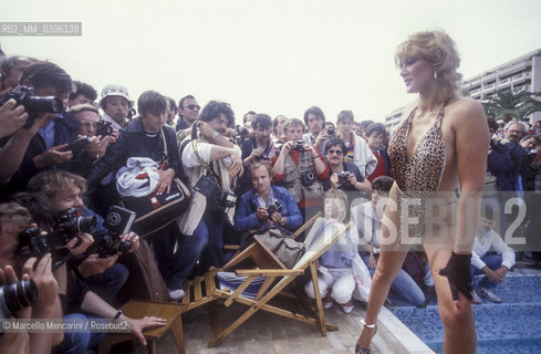37th Cannes Film Festival, 1984. Photographers shooting a starlet on the beach / 37° Festival di Cannes, 1984. Fotografi intorno a una starlette sulla spiaggia - ©Marcello Mencarini/Rosebud2