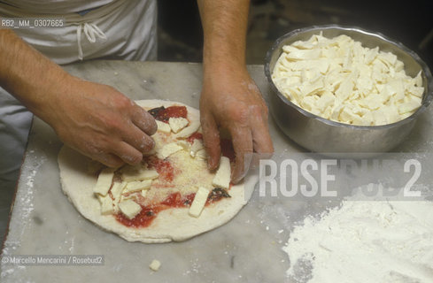 Naples, Italy. Preparation of Pizza Margherita at Brandi pizza restaurant, where in 1889 it was invented in honour of Queen Margaret (Margherita) of Savoy. Fifth step: sprinkle with Mozzarella cheese / Napoli, Preparazione della pizza Margherita nella Pizzeria Brandi, dove nel 1889 fu inventata in onore della regina Margherita di Savoia. Quinta fase: aggiungere mozzarella a pezzetti - ©Marcello Mencarini/Rosebud2