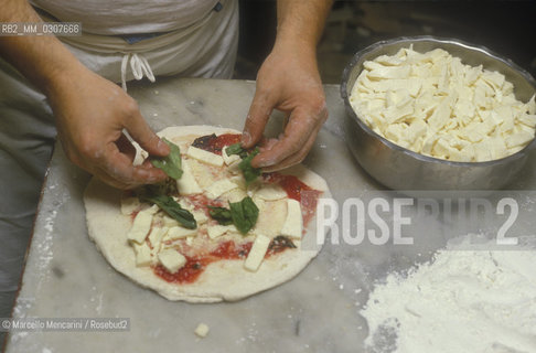 Naples, Italy. Preparation of Pizza Margherita at Brandi pizza restaurant, where in 1889 it was invented in honour of Queen Margaret (Margherita) of Savoy. Fifth step: sprinkle with Mozzarella cheese / Napoli, Preparazione della pizza Margherita nella Pizzeria Brandi, dove nel 1889 fu inventata in onore della regina Margherita di Savoia. Quinta fase: aggiungere mozzarella a pezzetti - ©Marcello Mencarini/Rosebud2