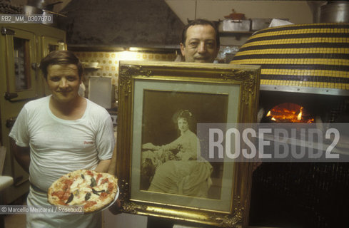 Naples, Italy. A Pizza Margherita prepared in the Brandi pizza restaurant, where in 1889 it was invented in honour of Queen  Margaret (Margherita) of Savoy, who appears in a vintage picture / Napoli, una pizza Margherita preparata nella Pizzeria Brandi, dove nel 1889 fu inventata in onore della regina Margherita di Savoia, che appare in una foto depoca - ©Marcello Mencarini/Rosebud2