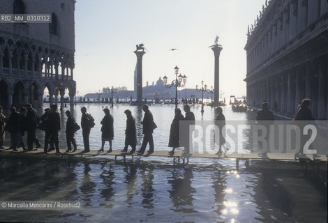 Venice, 1998. High Tide in St. Marks Square. People walking on the gangways / Venezia, 1998. Acqua alta in piazza San Marco. Passanti sulle passerelle - ©Marcello Mencarini/Rosebud2