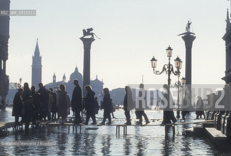 Venice, 1998. High Tide in St. Marks Square. People walking on the gangways / Venezia, 1998. Acqua alta in piazza San Marco. Passanti sulle passerelle - ©Marcello Mencarini/Rosebud2