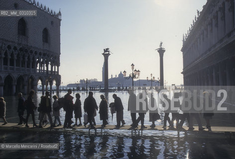 Venice, 1998. High Tide in St. Marks Square. People walking on the gangways / Venezia, 1998. Acqua alta in piazza San Marco. Passanti sulle passerelle - ©Marcello Mencarini/Rosebud2