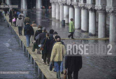Venice, 1998. High Tide in St. Marks Square. People walking on the gangways / Venezia, 1998. Acqua alta in piazza San Marco. Passanti sulle passerelle - ©Marcello Mencarini/Rosebud2