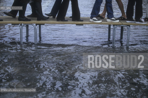 Venice, 1998. High Tide in St. Marks Square. People walking on the gangways / Venezia, 1998. Acqua alta in piazza San Marco. Passanti sulle passerelle - ©Marcello Mencarini/Rosebud2