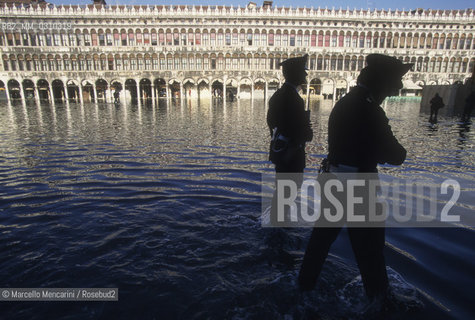 Venice, 1998. High Tide in St. Marks Square. Policemen walking in the water in front of the Procuratie Nuove / Venezia, 1998. Acqua alta in piazza San Marco. Carabinieri che camminano nellacqua davanti alla Procuratie Nuove - ©Marcello Mencarini/Rosebud2