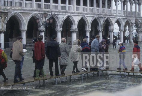 Venice, 1998. High Tide in St. Marks Square. People walking on the gangways / Venezia, 1998. Acqua alta in piazza San Marco. Passanti sulle passerelle - ©Marcello Mencarini/Rosebud2