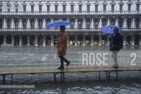 Venice, 1998. High Tide in St. Marks Square, in the background the Procuratie Nuove. People walking on the gangways / Venezia, 1998. Acqua alta in piazza San Marco, sullo sfondo le Procuratie nuove. Passanti sulle passerelle - ©Marcello Mencarini/Rosebud2