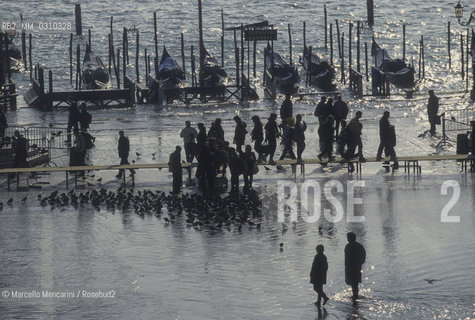 Venice, 1998. High Tide in St. Marks Square. People walking on the gangways / Venezia, 1998. Acqua alta in piazza San Marco. Passanti sulle passerelle - ©Marcello Mencarini/Rosebud2