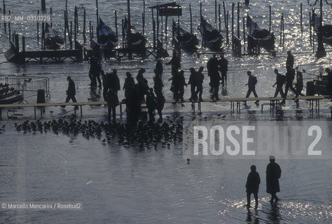 Venice, 1998. High Tide in St. Marks Square. People walking on the gangways / Venezia, 1998. Acqua alta in piazza San Marco. Passanti sulle passerelle - ©Marcello Mencarini/Rosebud2