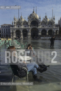 Venice, 1998. High Tide in St. Marks Square. Tourists sitting at an outdoor coffee table / Venezia, 1998. Acqua alta in Piazza San Marco. Turisti seduti a un tavolo allaperto di un bar - ©Marcello Mencarini/Rosebud2