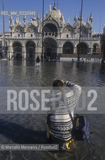 Venice, 1998. High Tide in St. Marks Square. A photograph in front of the St. Marks Basilica / Venezia, 1998. Acqua alta in Piazza San Marco. Fotografo di fronte alla basilica di San Marco - ©Marcello Mencarini/Rosebud2