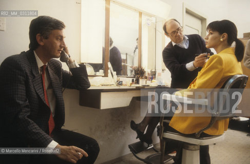 Rome, 1986. Italian TV journalist Piero Badaloni phoning in a dressing room in the RAI Italian public television studios, before conducting the television broadcast Uno mattina. On the right, co-host Elisabetta Gardini during the make-up / Roma, 1986. Il giornalista televisivo Piero Badaloni al telefono in camerino negli studi RAI, prima di condurre il programma televisivo Uno mattina. A destra, la co-conduttrice Elisabetta Gardini al trucco - ©Marcello Mencarini/Rosebud2