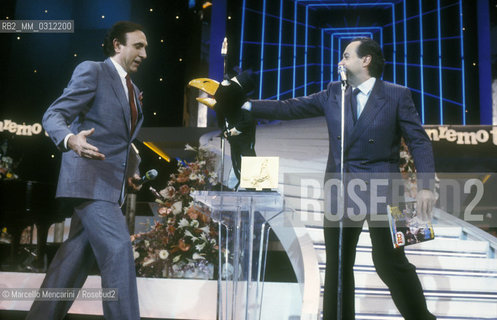 Sanremo Music Festival 1985. Italian TV presenter Pippo Baudo and ventriloquist José Luis Moreno performing with his crow puppet called Rockfeller / Festival di Sanremo 1985. Il presentatore tv Pippo Baudo e il ventriloquo José Luis Moreno con il suo personaggio, il corvo Rockfeller - ©Marcello Mencarini/Rosebud2