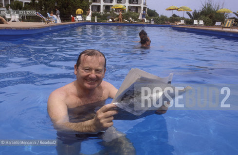Giardini Naxos (Messina), 1986. Italian journalist Gianni Bisiach  reads a newspaper in the swimming pool of Hilton Hotel / Giardini Naxos (Messina), 1986. Il giornalista Gianni Bisiach legge il giormnale nella piscina dellHotel Hilton -
 ©Marcello Mencarini/Rosebud2