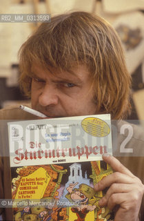 Bologna, 1981. Italian cartoonist Bonvi (Franco Bonvicini) in his studio holding an issue of his comic strip Sturmtruppern, 1981 / Il fumettista Bonvi (Franco Bonvicini) nel suo studio con un numero della sua striscia Sturmtruppen, 1981 - ©Marcello Mencarini/Rosebud2
