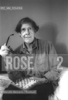 Venice, 1982. American composer John Cage sitting on the bed with a chessboard in his hotel room  / Venezia, 1982. Il compositore John Cage seduto sul letto con una scacchiera nella sua stanza dalbergo - ©Marcello Mencarini/Rosebud2