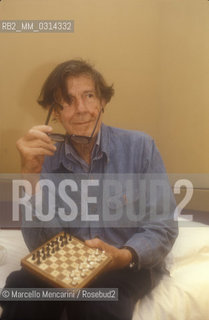 Venice, 1982. American composer John Cage sitting on the bed with a chessboard in his hotel room  / Venezia, 1982. Il compositore John Cage seduto sul letto con una scacchiera nella sua stanza dalbergo - ©Marcello Mencarini/Rosebud2