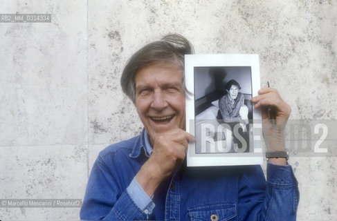Roma, 1983. American composer John Cage holding a photo of him taken in the previous year in Venice by the same photographer / Roma, 1983. Il compositore John Cage tiene in mano una sua foto scattata lanno precedente a Venezia dallo stesso fotografo - ©Marcello Mencarini/Rosebud2