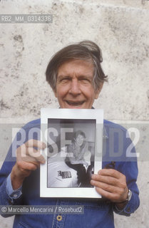 Roma, 1983. American composer John Cage holding a photo of him taken in the previous year in Venice by the same photographer / Roma, 1983. Il compositore John Cage tiene in mano una sua foto scattata lanno precedente a Venezia dallo stesso fotografo - ©Marcello Mencarini/Rosebud2