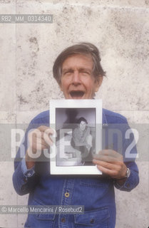 Roma, 1983. American composer John Cage holding a photo of him taken in the previous year in Venice by the same photographer / Roma, 1983. Il compositore John Cage tiene in mano una sua foto scattata lanno precedente a Venezia dallo stesso fotografo - ©Marcello Mencarini/Rosebud2