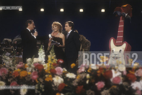 Sanremo Music Festival 1990. Festival TV presenters Johnny Dorelli and Gabriella Carlucci with Dorellis son, singer Gianluca Guid / Festival di Sanremo 1990. I presentatori del Festival Johnny Dorelli e Gabriella Carlucci con il figlio di Dorelli, il cantante Gianluca Guidi- ©Marcello Mencarini/Rosebud2