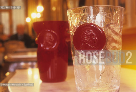 Venice, 1998. Caffè Florian. Goto de fornasa dedicated to Giacomo Casanova.  Goto de fornasa or goto de fornase in Venetian dialect means “furnace tumbler”, and is used to define the typical furnace tumbler that was originally created in Murano glass workshops as a workshop tumbler and was made using the types of glass available. They are now considered authentic works of art, original creations that allow the master glassblower to express his talent in a very free way / Venezia, 1998. Caffè Florian. Goto de fornasa dedicato a Casanova. Goto de fornasa o goto de fornase in dialetto veneziano significa bicchiere di fornace, cioè il tipico bicchiere che veniva creato nelle officine vetrarie di Murano originariamente per uso interno con il vetro rimasto a disposizione. Oggi sono considerati delle vere opere darte, creazioni originali dei maestri vetrai per esprimere liberamente il loro talento - ©Marcello Mencarini/Rosebud2
