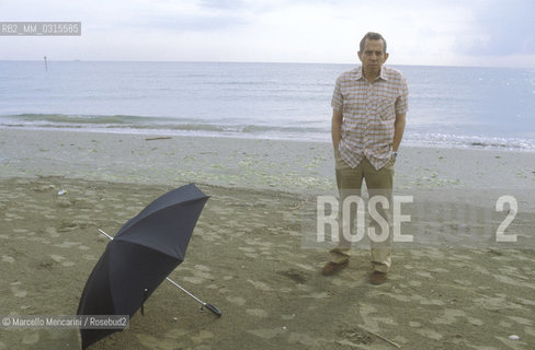 Venice, 1982. Italian composer Aldo Clementi holding an umbrella on the Lido seashore/ Venezia, 1982. Il compositore Aldo Clementi sulla spiaggia del Lido con un ombrello - ©Marcello Mencarini/Rosebud2