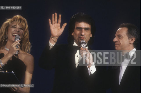 Sanremo Music Festival 1990. Festival TV presenters Gabriella Carlucci and Johnny Dorelli with, in the middle, Italian pop singer Toto Cutugno, finished in second place with the song Gli amori / Festival di Sanremo 1990. I presentatori del Festival Gabriella Carlucci e  Johnny Dorelli con, al centro, il cantante Toto Cutugno, classificato al secondo posto con la canzone Gli amori - ©Marcello Mencarini/Rosebud2