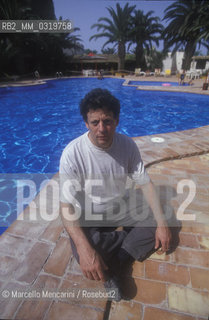 Gibellina (Trapani) 1994. Composer Philip Glass on the edge of the swimming pool of his hotel in the days of the rehearsals before the premiere of his opera for ensemble and film La Belle et la Bête / Gibellina (Trapani) 1994. Il compositore Philip Glass sul bordo della piscina del suo albergo nei giorni delle prove per la prima della sua opera La belle et la bête - ©Marcello Mencarini/Rosebud2