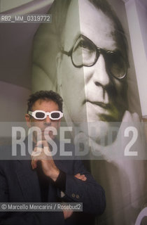 Rome, 1998. American composer Philip Glass wearing glasses to see three-dimensional images. He is in Rome at the Olympic Theater for the 3D opera Monsters of Grace, composed by him with Bob Wilson. A photo of Bob Wilson is in background / Roma, 1998. Il compositore Philip Glass con degli occhiali per immagini tridimensionali, a Roma al Teatro Olimpico con lopera Monster of Grace, scritta da lui in collaborazione con Bob Wilson. Sullo sfondo una foto di Bob Wilson - ©Marcello Mencarini/Rosebud2