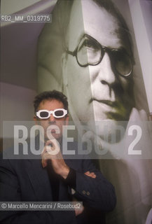 Rome, 1998. American composer Philip Glass wearing glasses to see three-dimensional images. He is in Rome at the Olympic Theater for the 3D opera Monsters of Grace, composed by him with Bob Wilson. A photo of Bob Wilson is in background / Roma, 1998. Il compositore Philip Glass con degli occhiali per immagini tridimensionali, a Roma al Teatro Olimpico con lopera Monster of Grace, scritta da lui in collaborazione con Bob Wilson. Sullo sfondo una foto di Bob Wilson - ©Marcello Mencarini/Rosebud2
