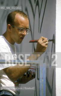 Artist Keith Haring working at the mural Tuttomondo on the rear wall of the Church of SantAntonio in Pisa, 1989 / Lartista Keith Haring mentre lavora al murale Tuttomondo sul muro posteriore della chiesa di SantAntonio abate a Pisa, 1989 - ©Marcello Mencarini/Rosebud2