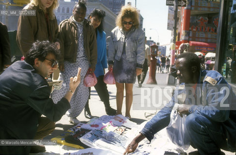 Sanremo in the World Tour 1990. Italian pop singer Pino Mango buying a t-shirt from a street vendor in New York City / Sanremo nel mondo 1990. Il cantante Pino Mango mentre compra una maglietta da un venditore ambulante a New York - ©Marcello Mencarini/Rosebud2